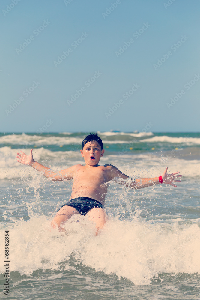 Happy boy running and jumping at shallow sea water