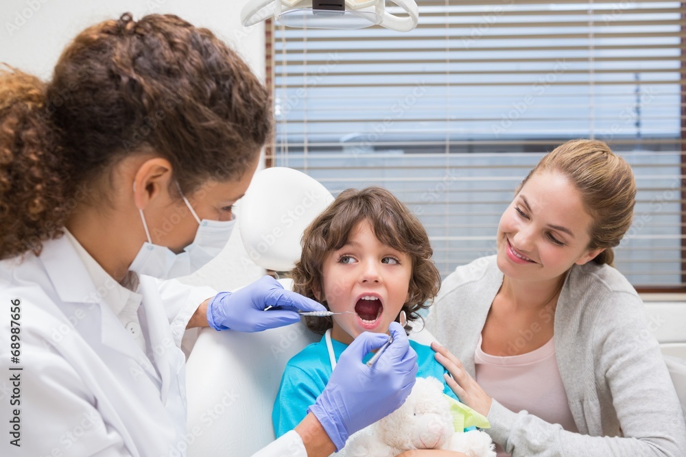 Pediatric dentist examining a little boys teeth with his mother Pediatric dentist examining a little boys teeth with his mother