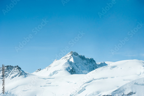 Beautiful snow-capped mountains against the blue sky © stnazkul