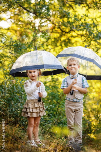 Children with umbrellas under sunny rain