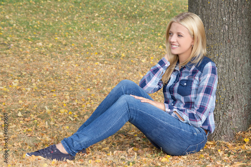 portrait of beautiful woman sitting in autumn park