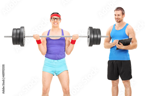 Guy lifting weight with fitness coach beside him