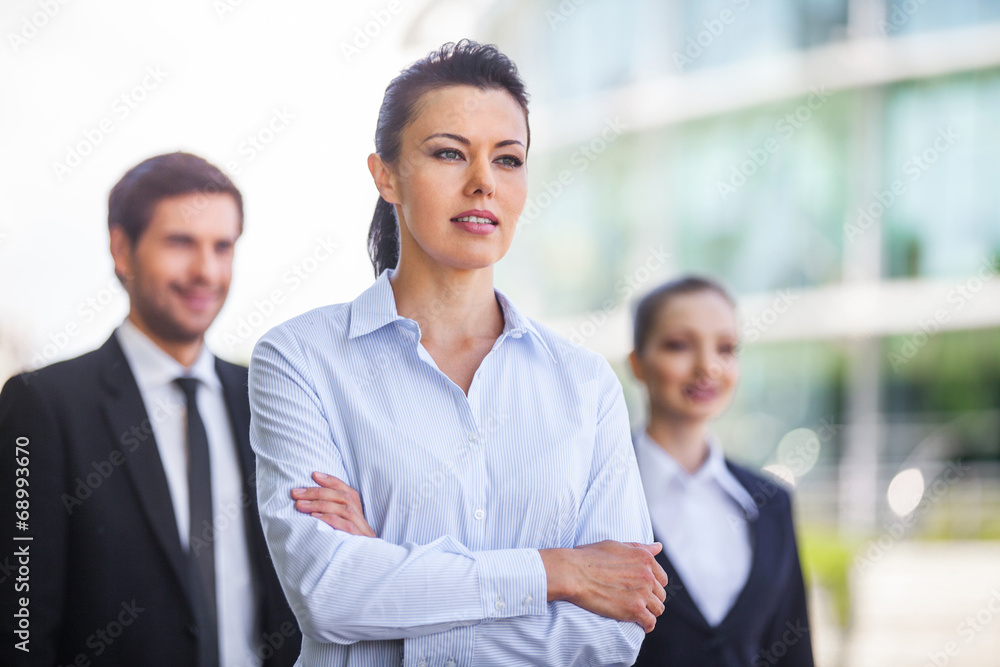 Three smiling business people standing outside. Three smiling business people standing outside.