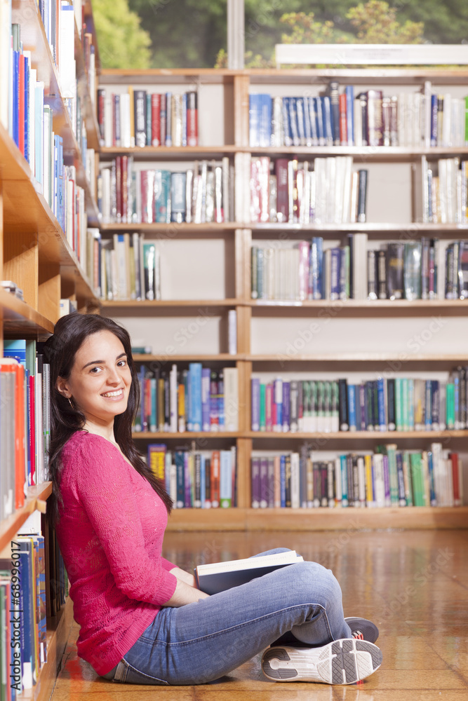 Portrait of a smiling young student reading a book in a library Portrait of a smiling young student reading a book in a library