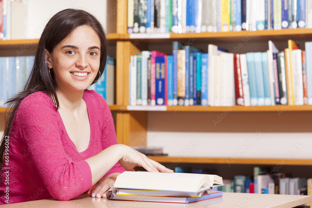 Smiling female student studying in a library Smiling female student studying in a library