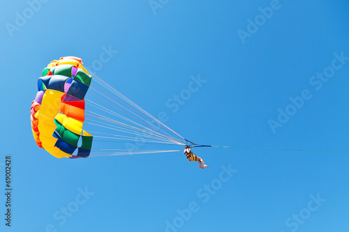 woman parasailing on parachute in blue sky photo