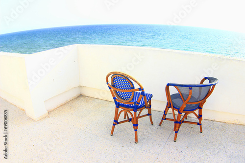 Romantic dating. Two blue chairs on terrace with sea view.