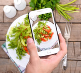 Hands taking photo vegetable salad with smartphone