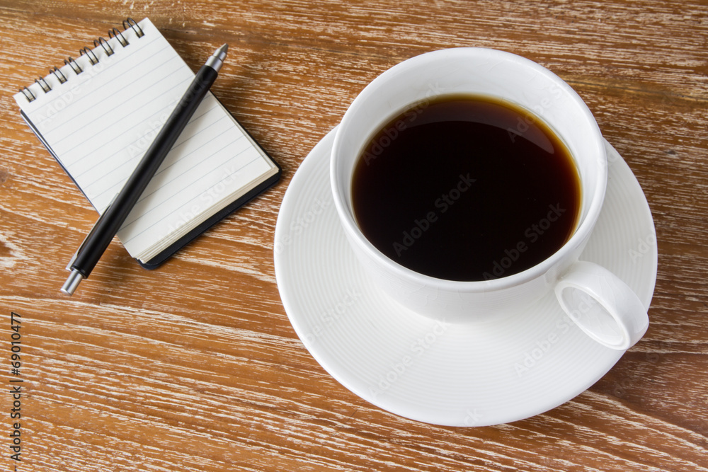 Cup of coffee on wooden table with notebook Cup of coffee on wooden table with notebook