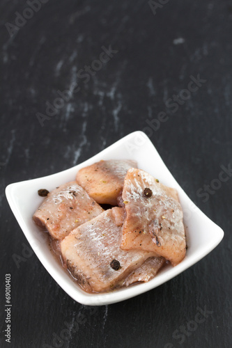 herring in white dish on black background