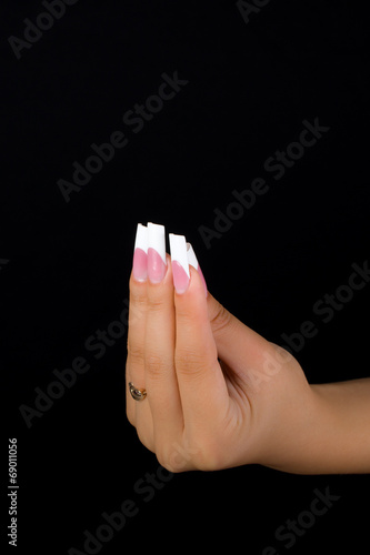 Fingers with white nails holding something