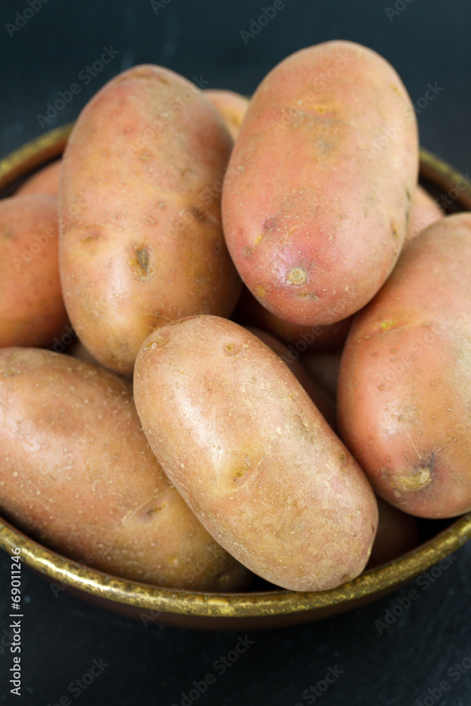 raw potato in dish on black background raw potato in dish on black background