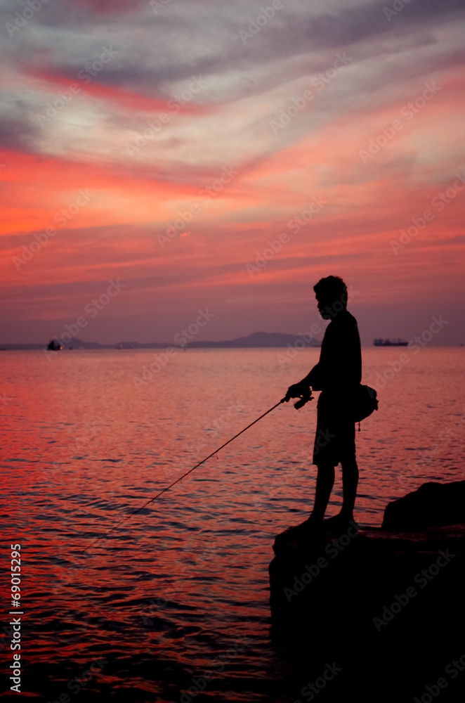 Silhouette of fishing man beside the sea