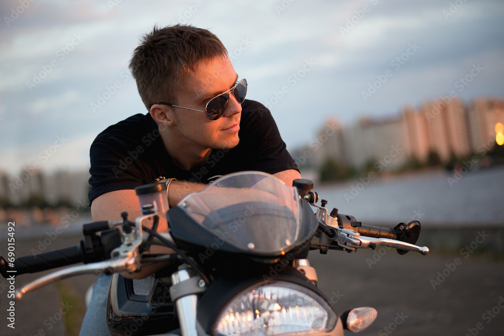 Romantic portrait handsome biker man  sits on a bike