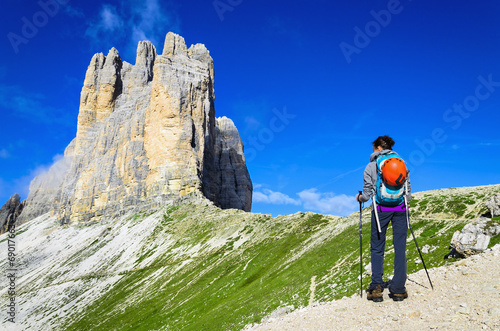 Woman hiker on mountain trail with view of Tre Cime, Dolomites