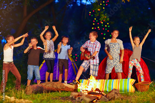 happy kids dancing around campfire