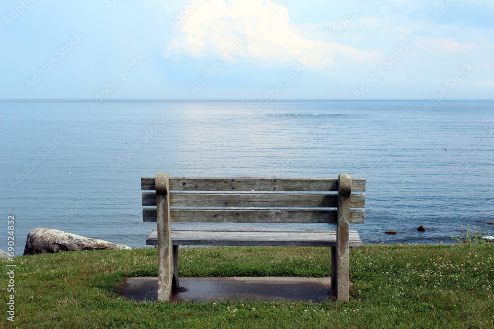 cement and wood bench on a cliff overlooking a calm sea
