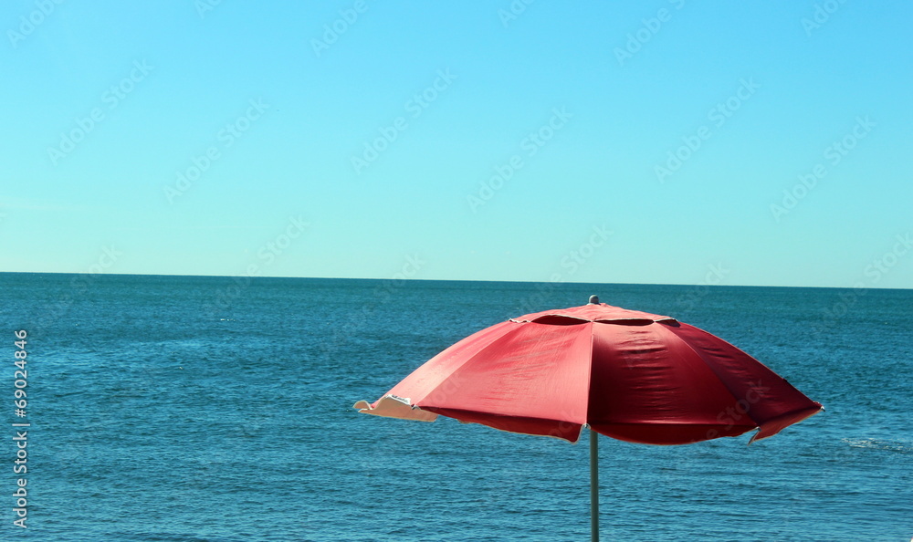 bright red umbrella blowing in the breeze at an ocean beach