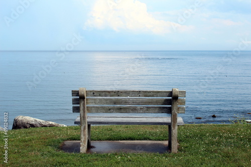 cement and wood bench on a cliff overlooking a calm sea