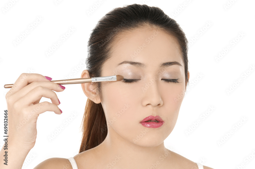 Charming young woman applying blusher eyelid Charming young woman applying blusher eyelid