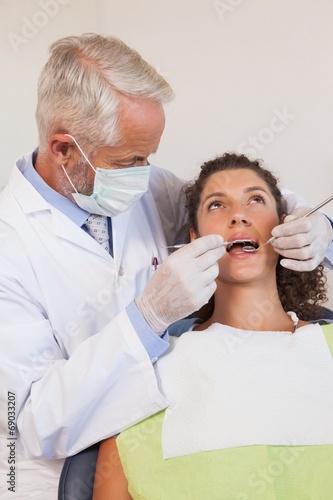 Dentist examining a patients teeth in the dentists chair