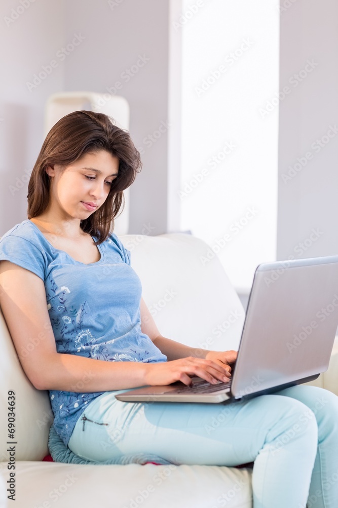 Pretty brunette relaxing on the couch using laptop Pretty brunette relaxing on the couch using laptop