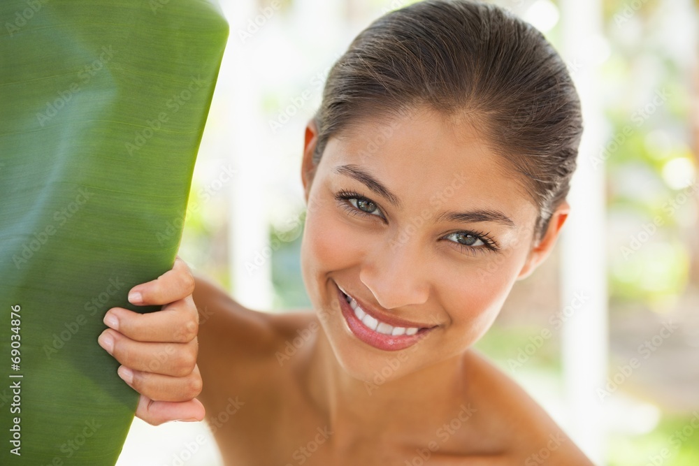 Beautiful brunette smiling at camera behind leaf Beautiful brunette smiling at camera behind leaf