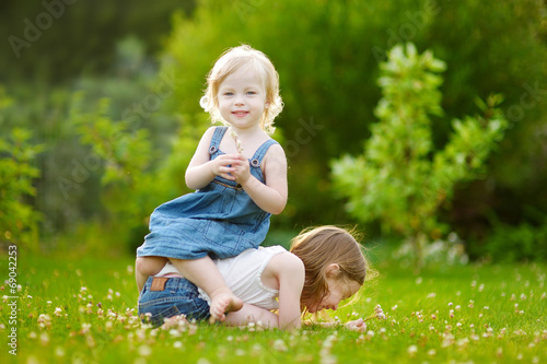 Two sisters having fun while sitting on the grass