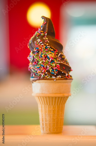 Ice cream cone with chocolate and rainbow color sprinkles on blu
