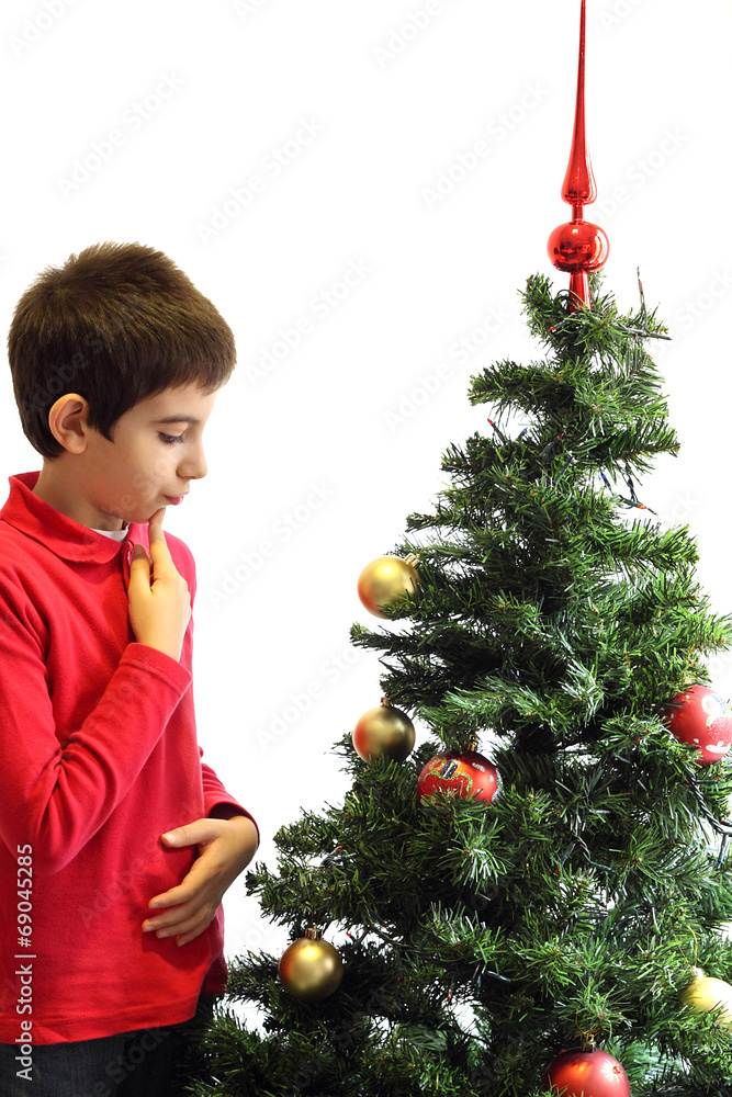 Young boy thinking in front of a Christmas tree Young boy thinking in front of a Christmas tree