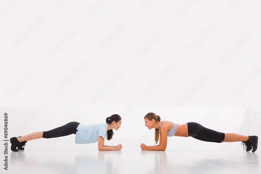 Two young woman doing push-ups in gym Two young woman doing push-ups in gym