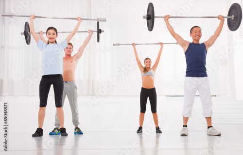 Multiethnic group of people exercising with weightlifting bar in