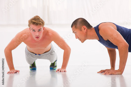 Two young male doing push-ups in gym