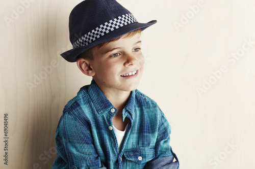 Young boy wearing checked shirt and hat.