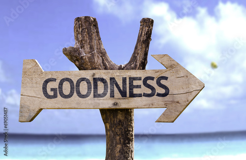 Goodness wooden sign with a beach on background