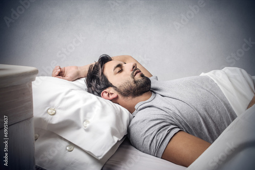 man deeply asleep in his bed