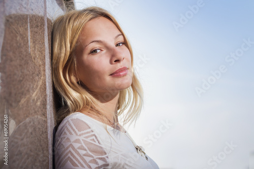 The beautiful girl costs at a wall having nestled