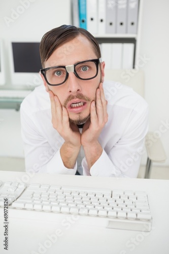 Nerdy nervous businessman working on computer