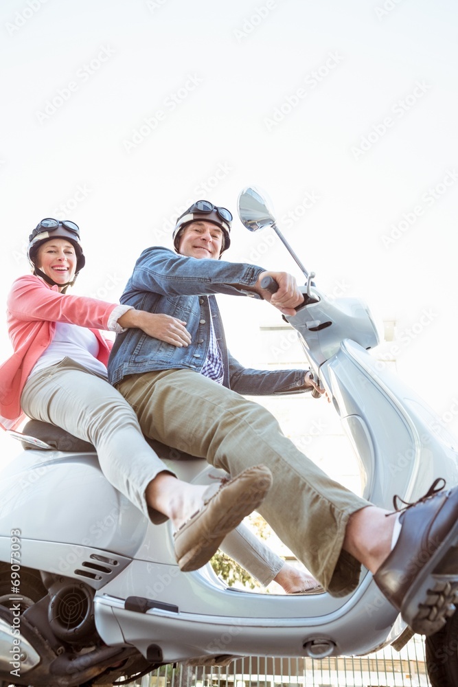 Naklejka premium Happy senior couple riding a moped