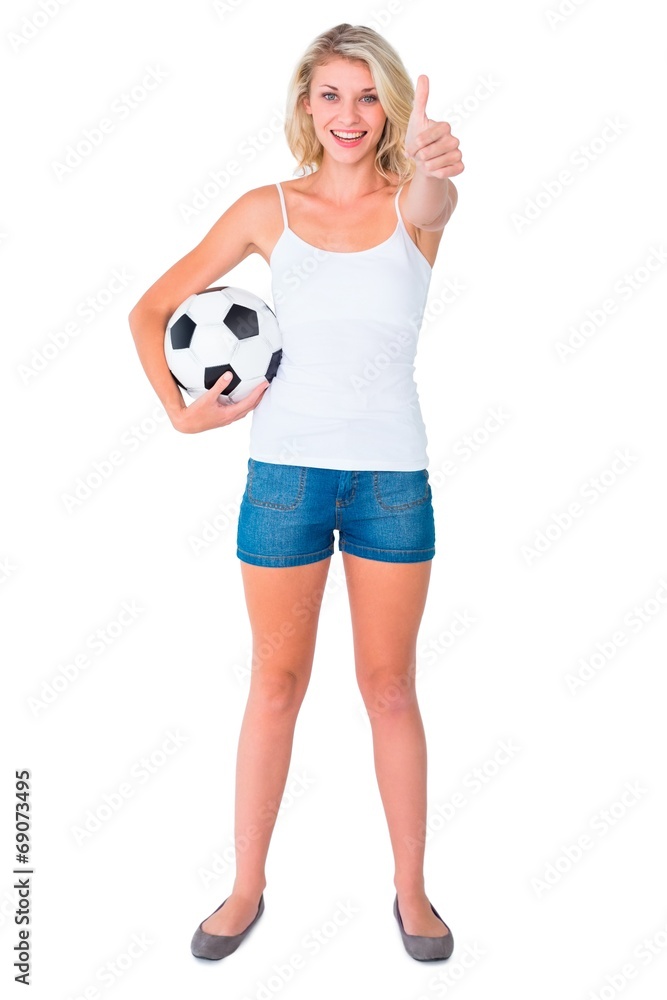 Pretty blonde football fan holding ball showing thumbs up Pretty blonde football fan holding ball showing thumbs up