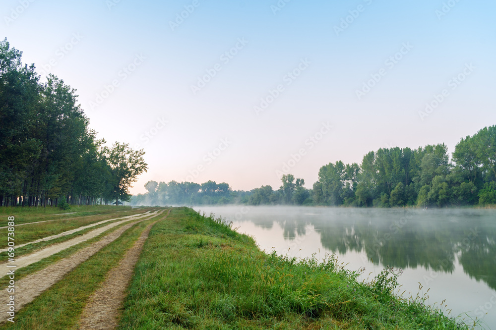 Path by the lake at foggy morning