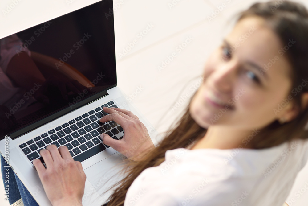 Naklejka premium relaxed young woman at home working on laptop computer
