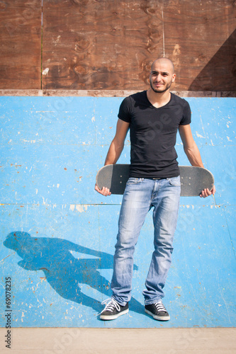 Skateboarder portrait standing on halfpipe at skate park.