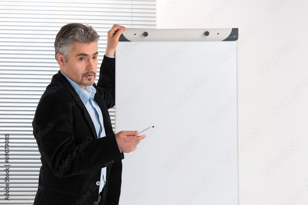 Mature businessman making presentation on flipchart. Mature businessman making presentation on flipchart.