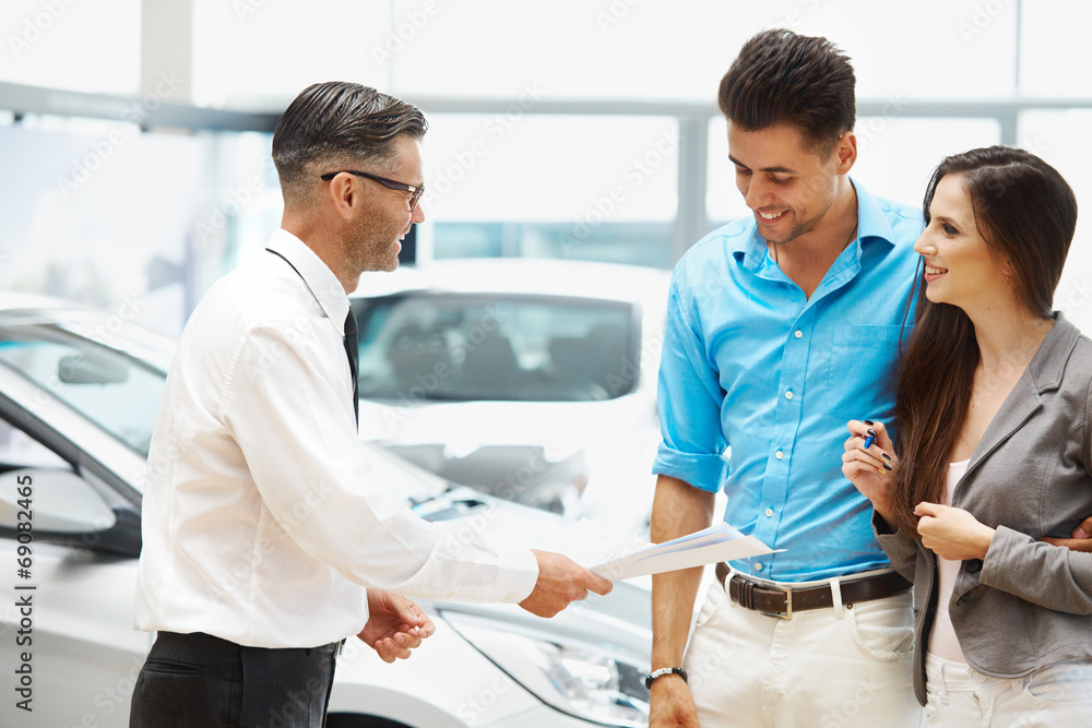 Young Couple Signing a Contract in Car Showroom. Young Couple Signing a Contract in Car Showroom.