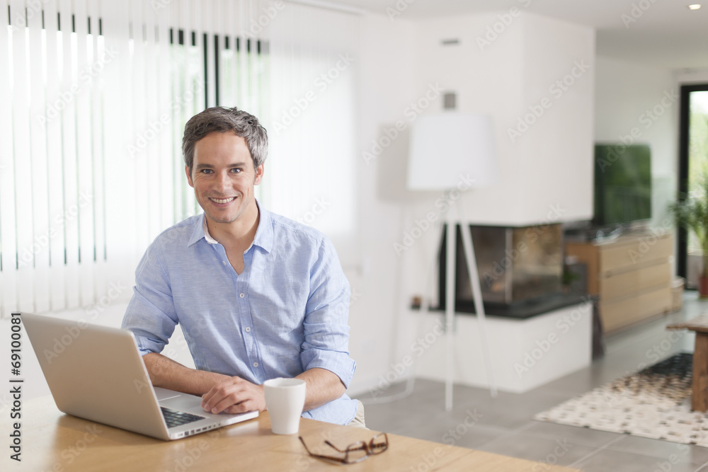 attractive man is using a laptop at home attractive man is using a laptop at home
