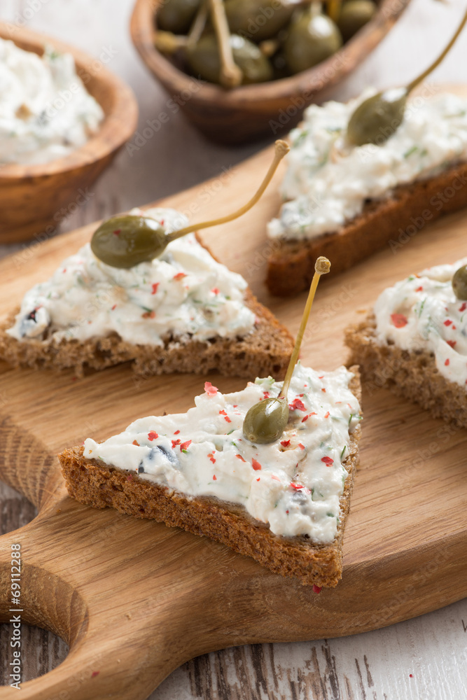 toasts with cheese pate and capers, vertical