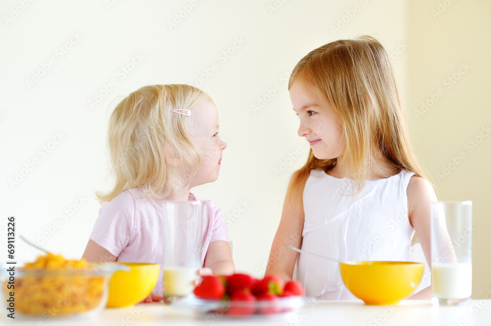 Two sisters eating cereal with milk Two sisters eating cereal with milk