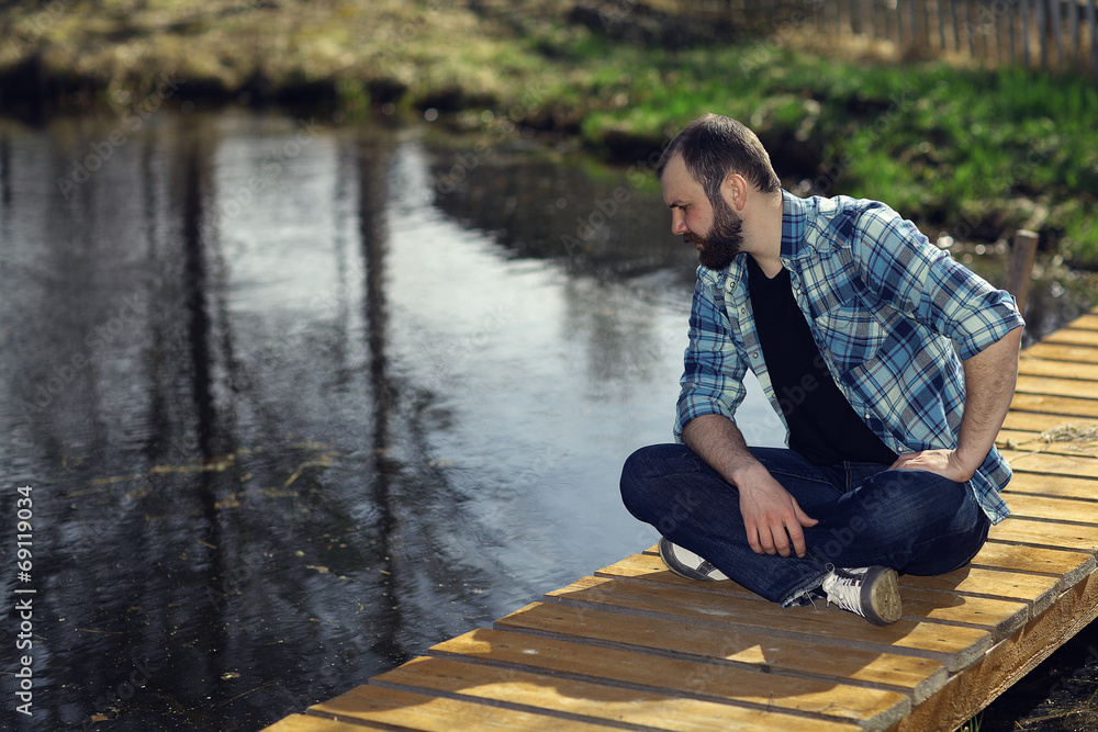 Fototapeta premium man meditating on the bank of a pond