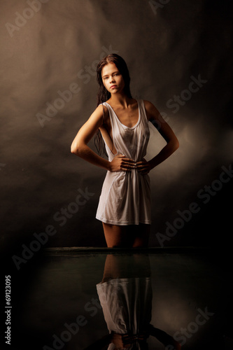 Girl in a white shirt standing in water on a black background.